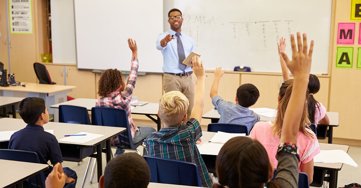 Kids raising their hands in class.