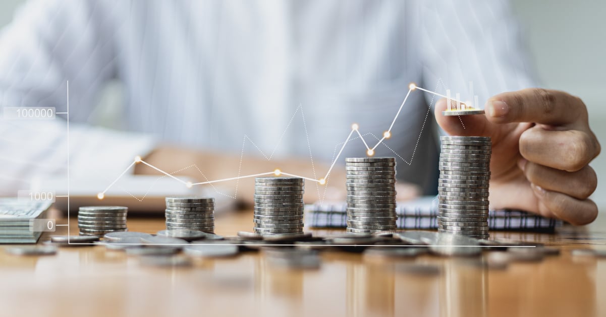 A business man adding to a gradually growing series of coins representing that every little bit of savings adds up for a business.