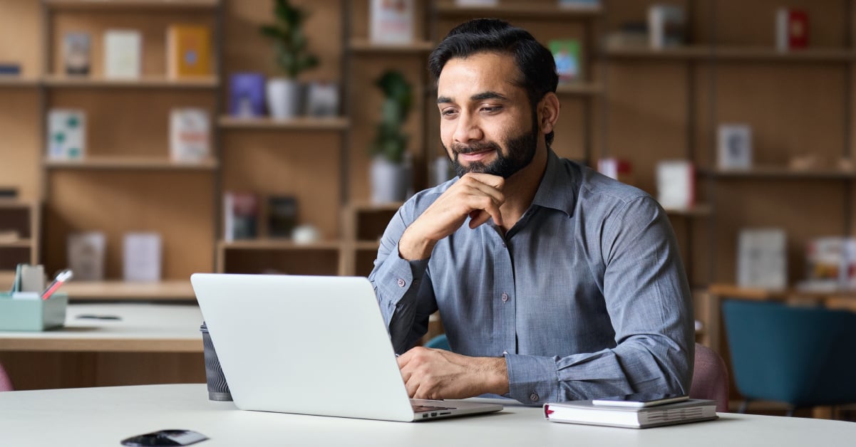 A male small business owner using his laptop to research the best business printer that will save them the most money over time. 