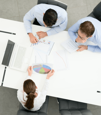 A group of workers compares the features and benefits of cloud voice vs. unified communications in a boardroom. 